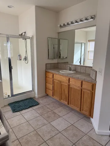 a spacious bathroom with a granite countertop sink a mirror and a shower