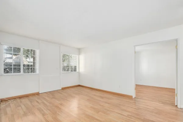 a view of empty room with wooden floor and fan