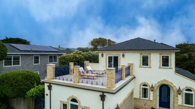 a view of a white house with large windows and a table and chairs
