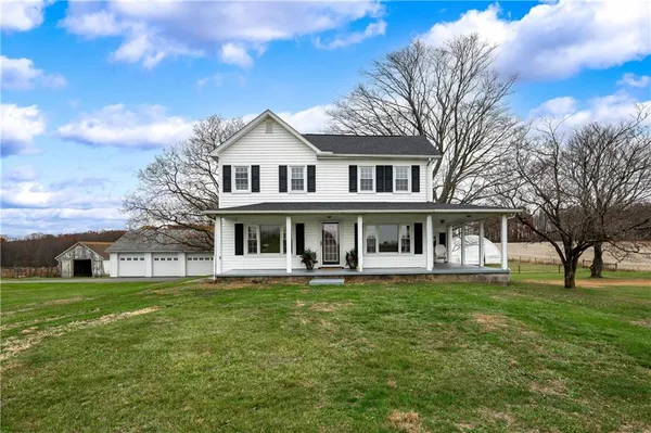 a view of a house with a big yard and large trees