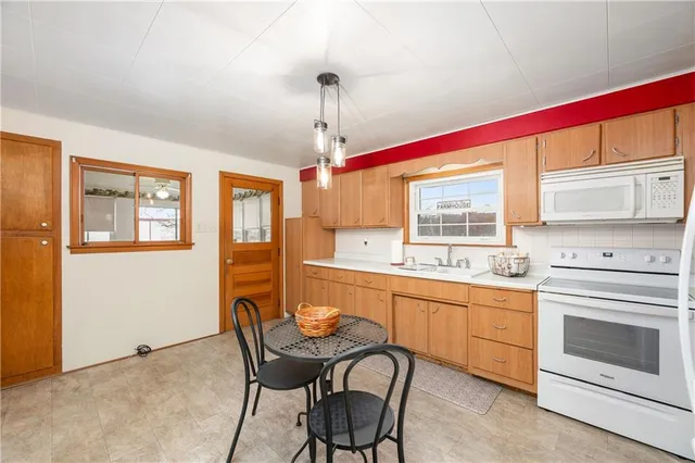 a kitchen with stainless steel appliances granite countertop a stove top oven a sink dishwasher a dining table and chairs with wooden floor