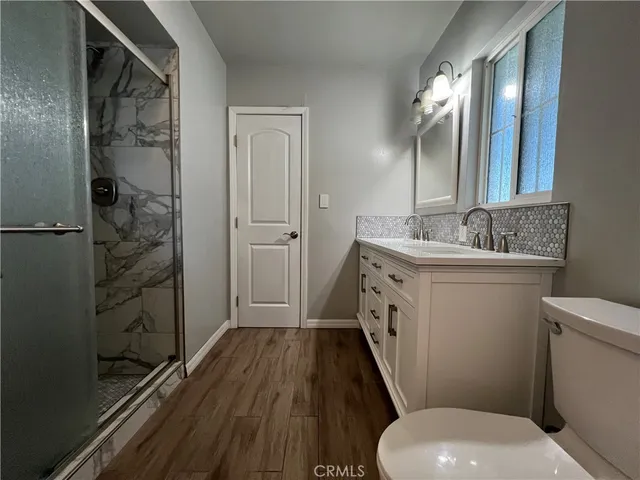 a bathroom with a sink a toilet a mirror and shower