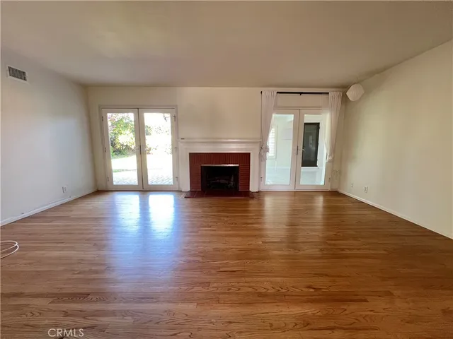 a view of a livingroom with wooden floor and a fireplace