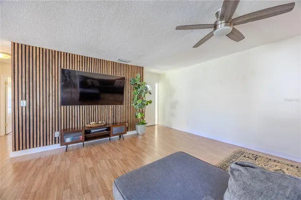 an empty room with wooden floor windows and a ceiling fan