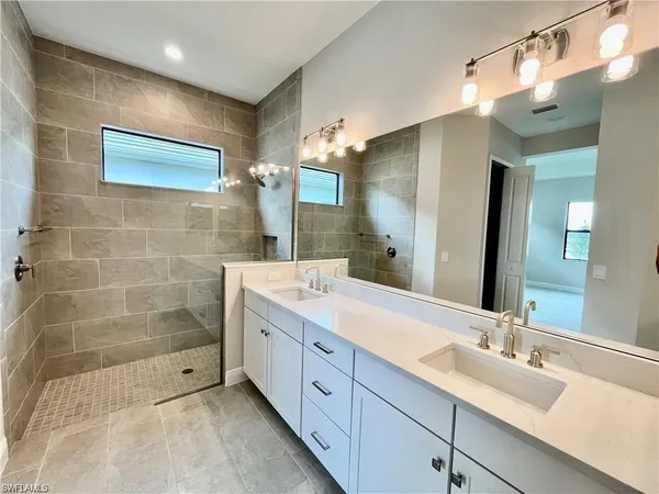 a bathroom with a double vanity sink mirror and shower