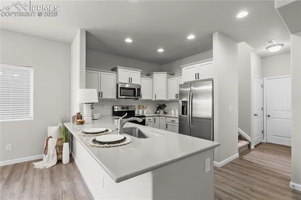 a kitchen that has a lot of white cabinets and stainless steel appliances
