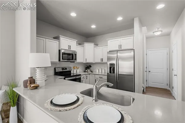 a kitchen with stainless steel appliances granite countertop a sink a stove a refrigerator cabinets and chairs