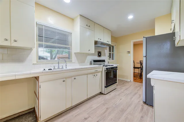 a kitchen with white cabinets and wooden floor