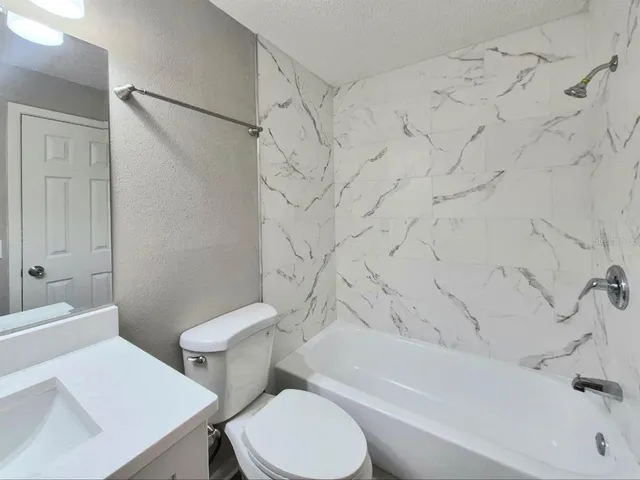 a bathroom with a sink a toilet a mirror a vanity and shower