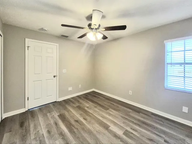 an empty room with wooden floor and ceiling fan