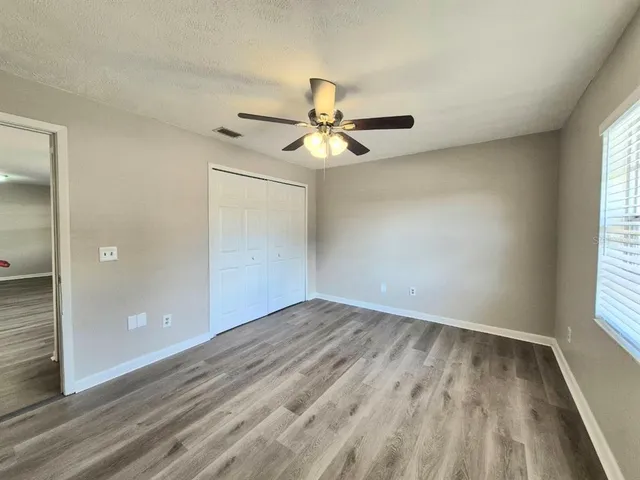 an empty room with wooden floor and ceiling fan