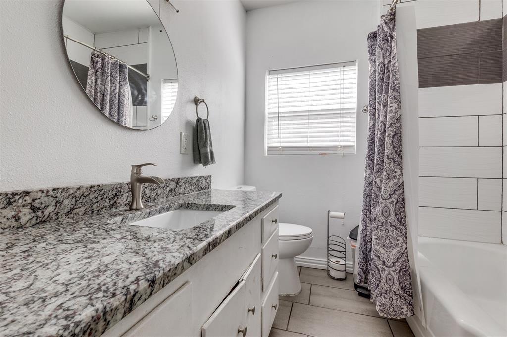 617 Haines Avenue Dallas, TX 75208 - Photo 18 of 29 a bathroom with a granite countertop sink a toilet and mirror