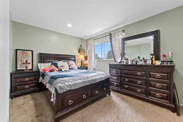 a bedroom with a bed and a mirror on dresser