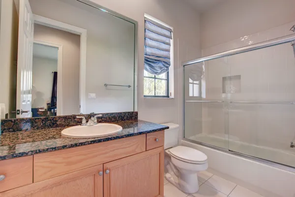 a bathroom with a granite countertop sink toilet a mirror and shower