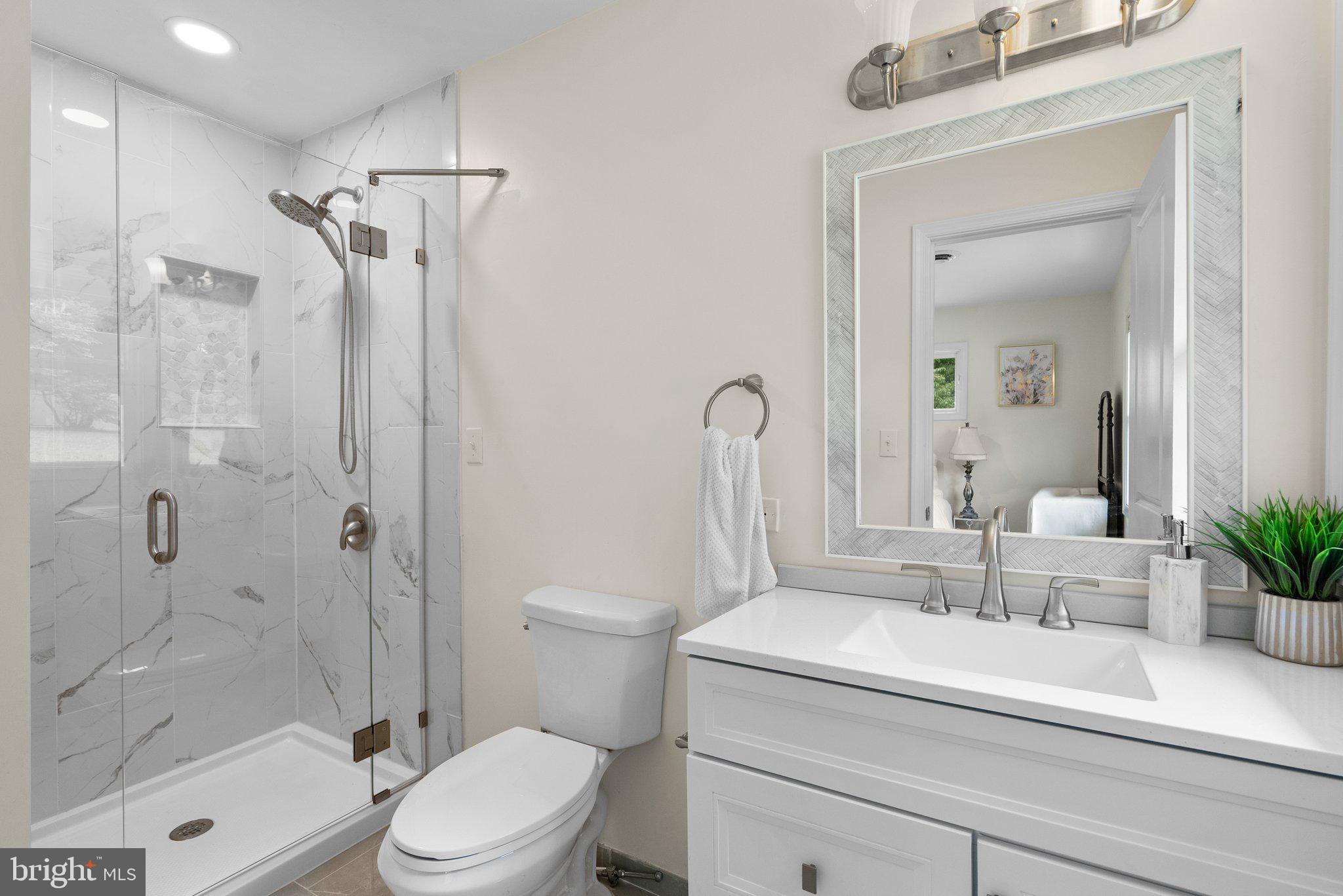 6906 Deer Valley Road Highland, MD 20777 - Photo 9 of 34 a bathroom with a sink a toilet a glass door a shower and a mirror