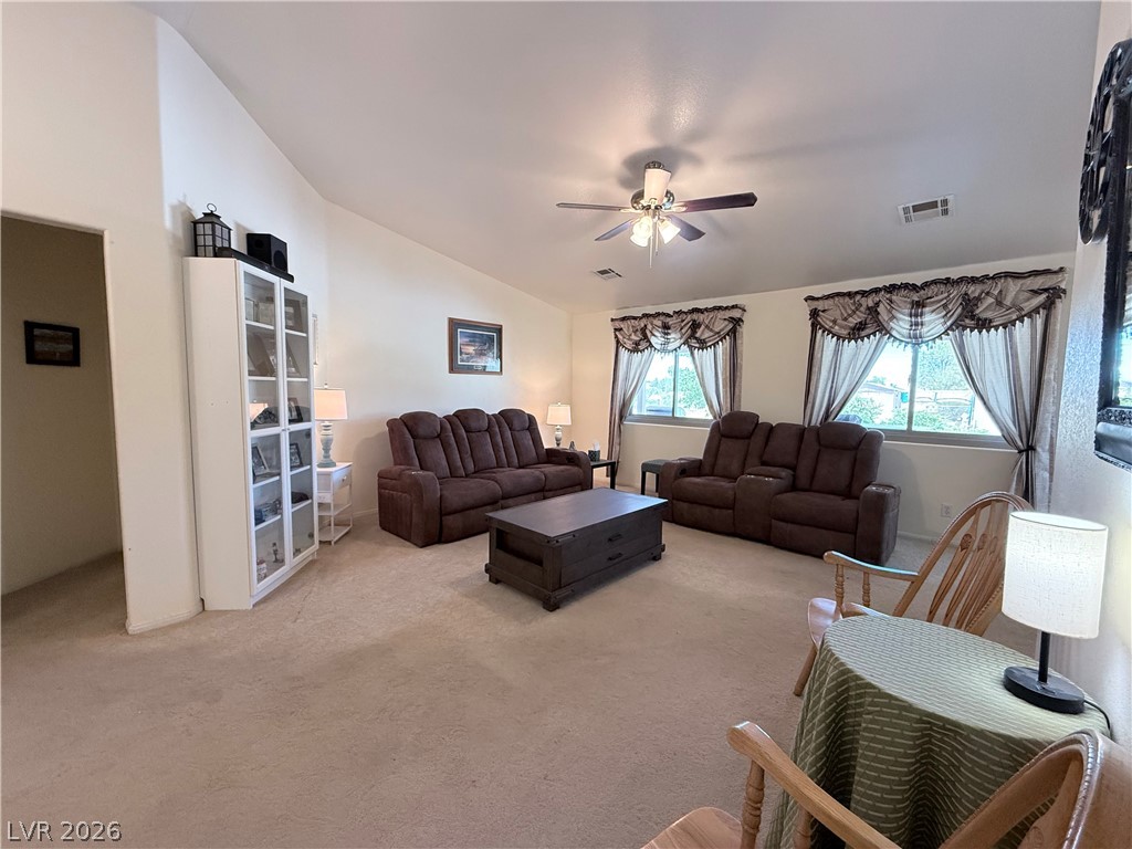1220 East Gamebird Road Pahrump, NV 89048 - Photo 5 of 49 A comfortable living space boasts a vaulted ceiling and ample natural light through well-appointed windows.