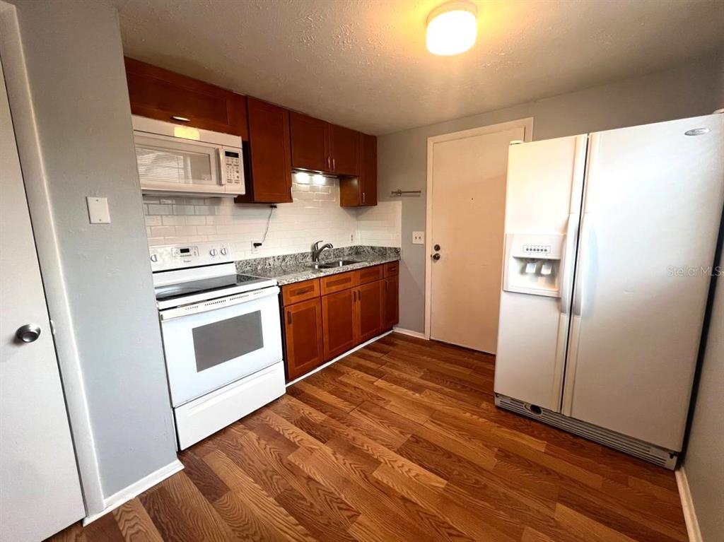 9406 Eastfield Road, Unit C Thonotosassa, FL 33592 - Photo 6 of 16 a kitchen with stainless steel appliances granite countertop a stove a sink and a refrigerator