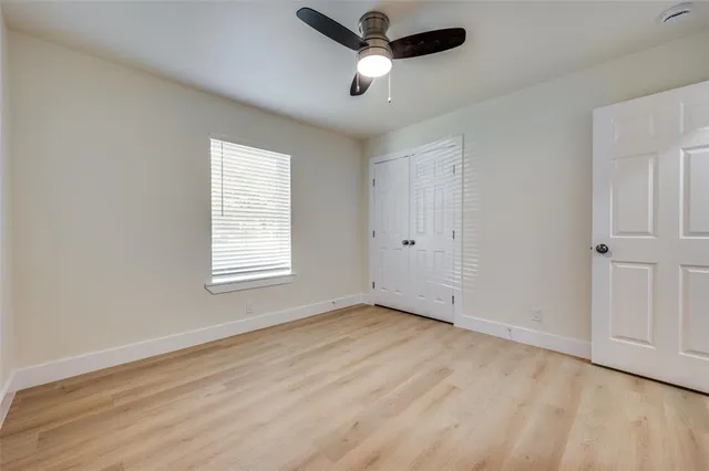 a view of empty room with wooden floor and fan