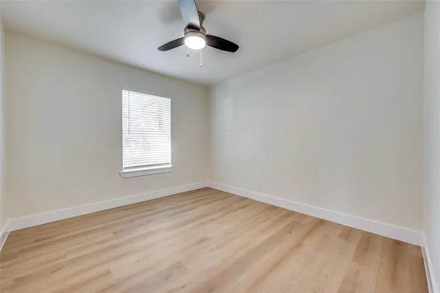 an empty room with a window and a ceiling fan