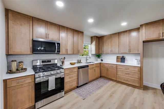 a kitchen with granite countertop wooden cabinets stainless steel appliances and a sink