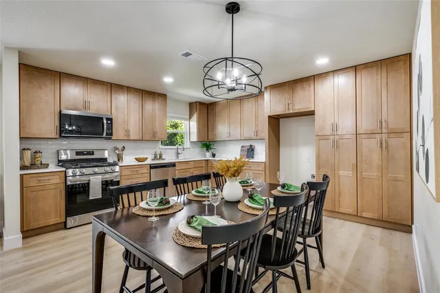 a view of a dining room with furniture a kitchen and chandelier