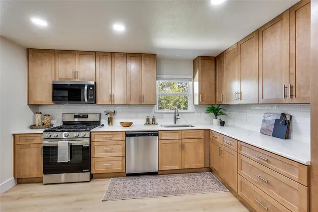 a kitchen with stainless steel appliances granite countertop a stove a sink dishwasher and a microwave oven with wooden floor