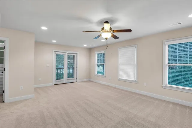 a view of a livingroom with a fireplace a ceiling fan and windows