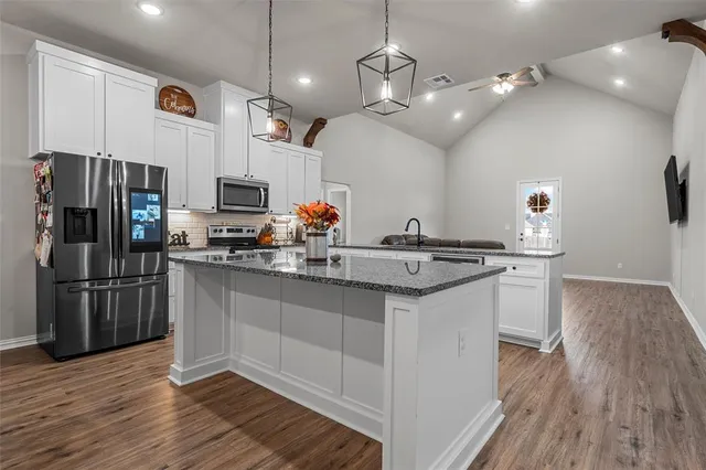 a kitchen with kitchen island a counter space a sink appliances and cabinets