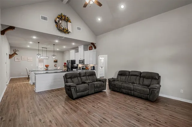 a living room with furniture kitchen view and a wooden floor