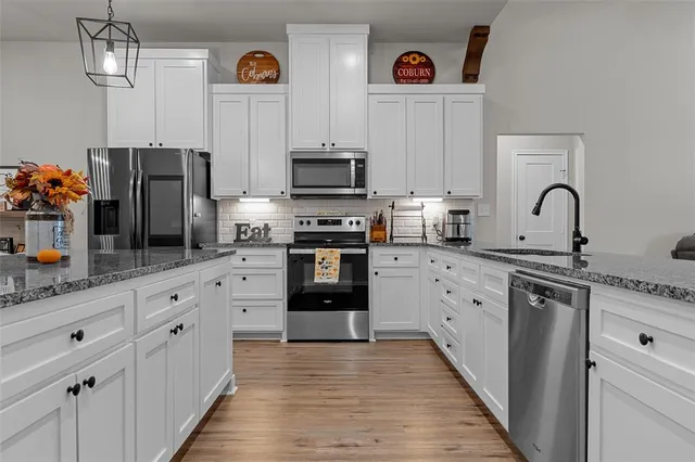 a kitchen with stainless steel appliances granite countertop a sink a stove and a wooden floors