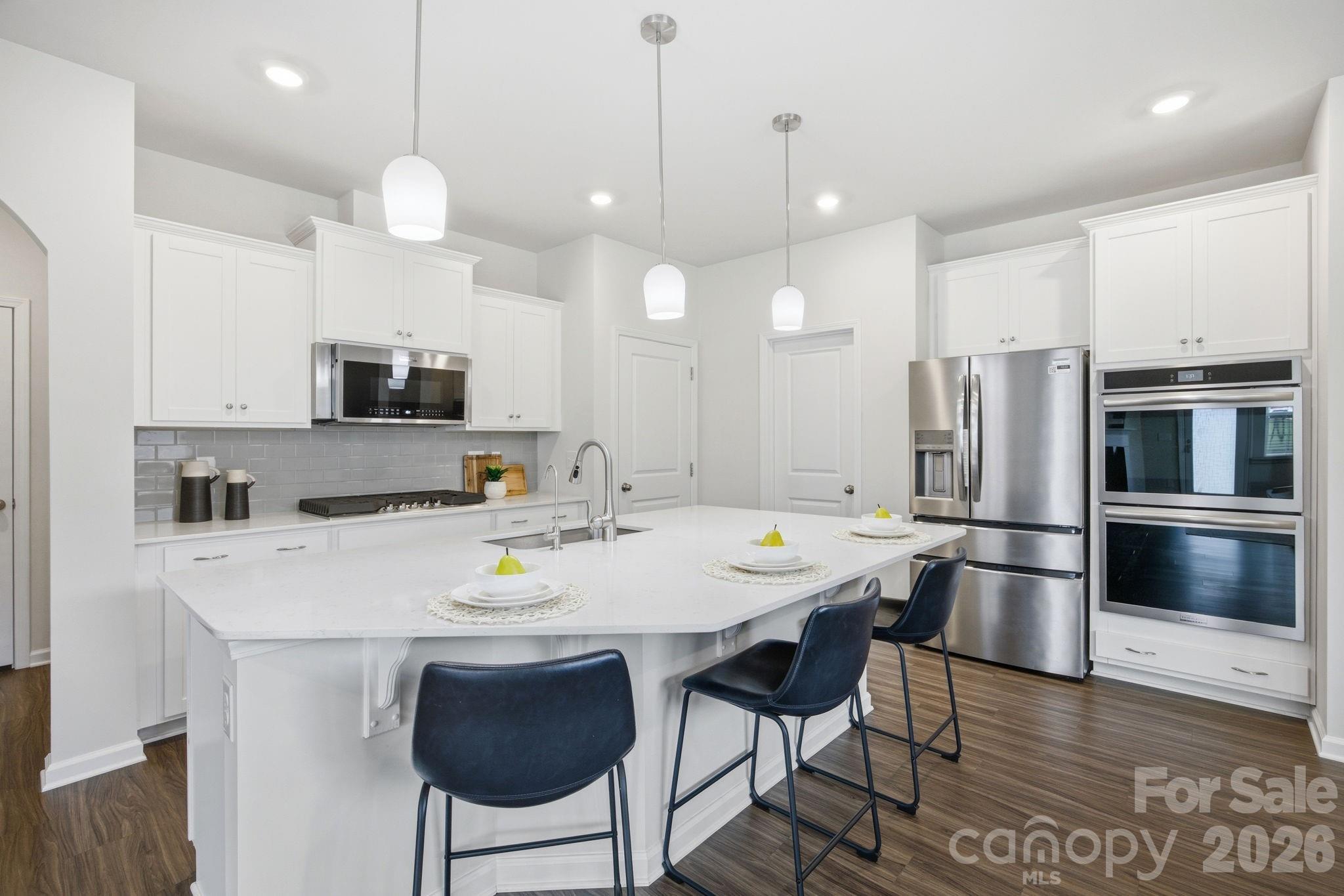 234 Hamptons Cove Road Troutman, NC 28166 - Photo 6 of 32 a kitchen with kitchen island appliances and wooden floor