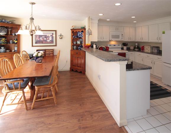 31 Cold Spring Drive, Unit B Sutton, MA 01590 - Photo 7 of 23 a kitchen with stainless steel appliances granite countertop a stove top oven a sink a dining table and chairs with wooden floor