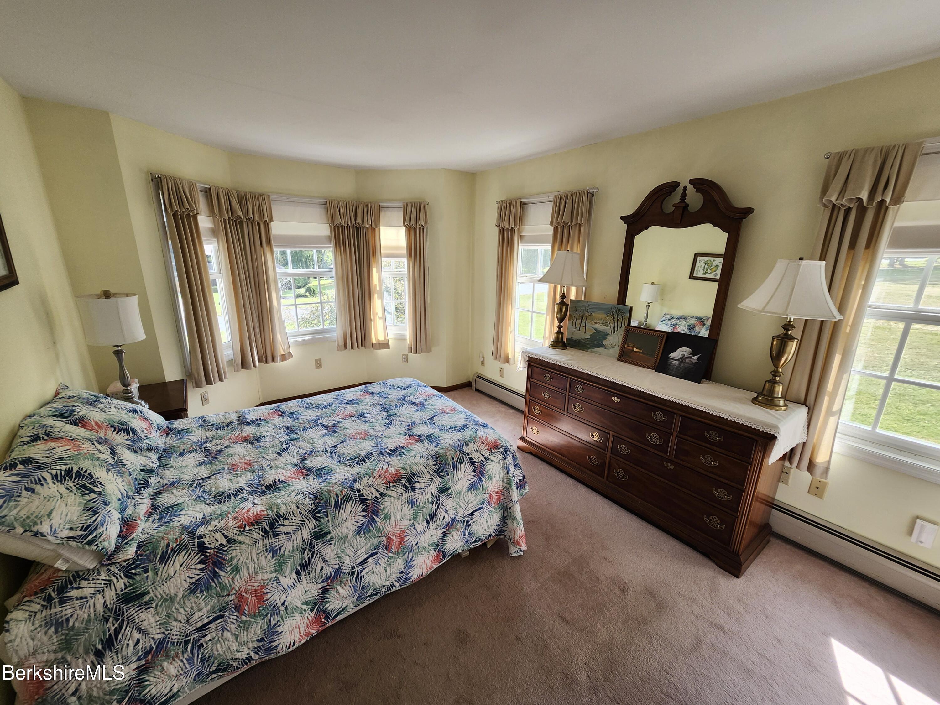 10 Lillybrook Road Pittsfield, MA 01201 - Photo 76 of 91 a bedroom with a bed lamp on dresser and a large mirror next to a window