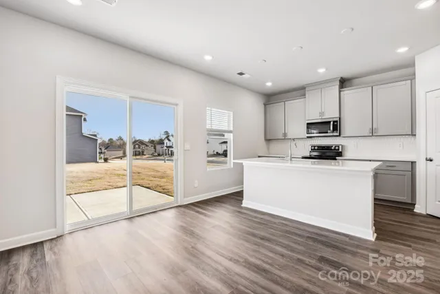 a view of kitchen with granite countertop stainless steel appliances refrigerator sink and cabinets