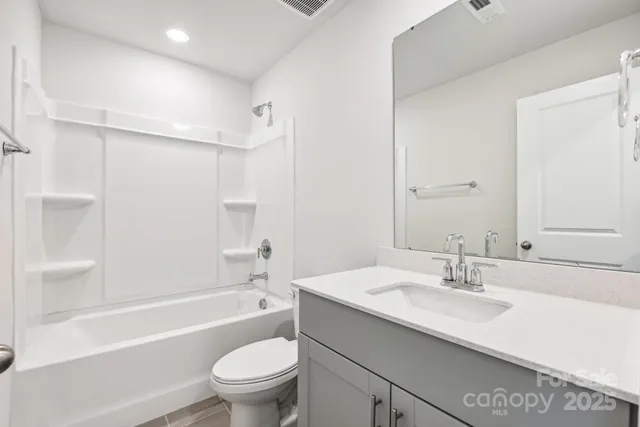 a bathroom with a granite countertop sink a toilet and shower