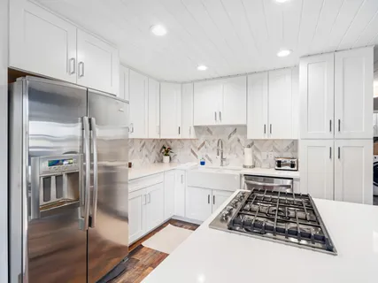 a kitchen with white cabinets and appliances