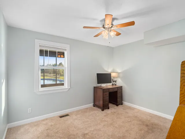 an empty room with windows and fan