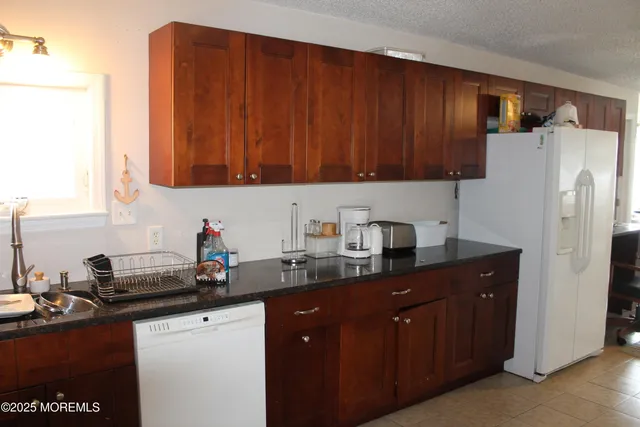 a kitchen with stainless steel appliances granite countertop a refrigerator a sink dishwasher a dining table and chairs with wooden floor