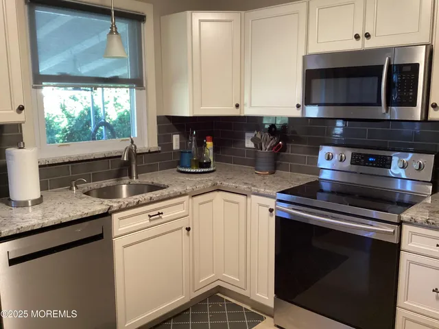 a kitchen with stainless steel appliances granite countertop a sink stove and microwave
