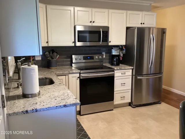 a kitchen with stainless steel appliances granite countertop a stove a refrigerator and a microwave