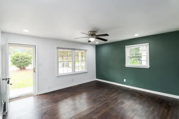a view of a big room with wooden floor and windows