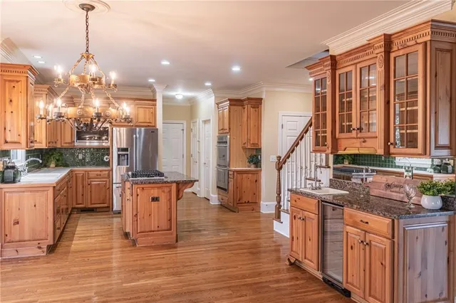 a large kitchen with stainless steel appliances kitchen island granite countertop a large counter top space a sink a refrigerator and cabinets