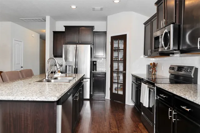 a kitchen with stainless steel appliances granite countertop a sink a stove and a refrigerator