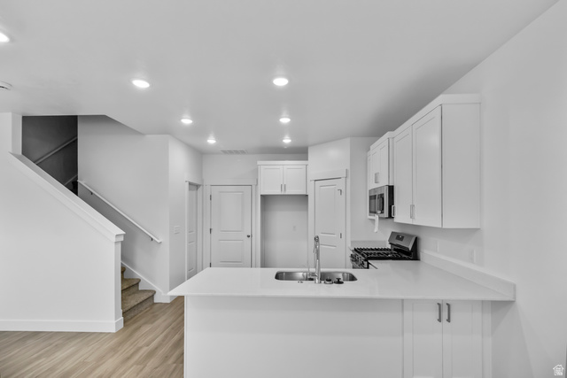 3014 South 265th Street West Logan, UT 84321 - Photo 7 of 25 Contemporary kitchen featuring white cabinetry and countertops, a stainless steel sink with a gooseneck faucet, a built-in microwave, and a gas range