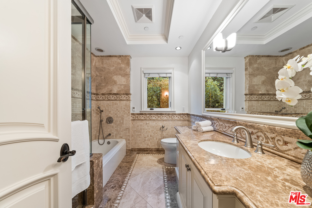 210 North Rockingham Avenue Los Angeles, CA 90049 - Photo 37 of 50 a bathroom with a granite countertop sink mirror vanity and a bathtub