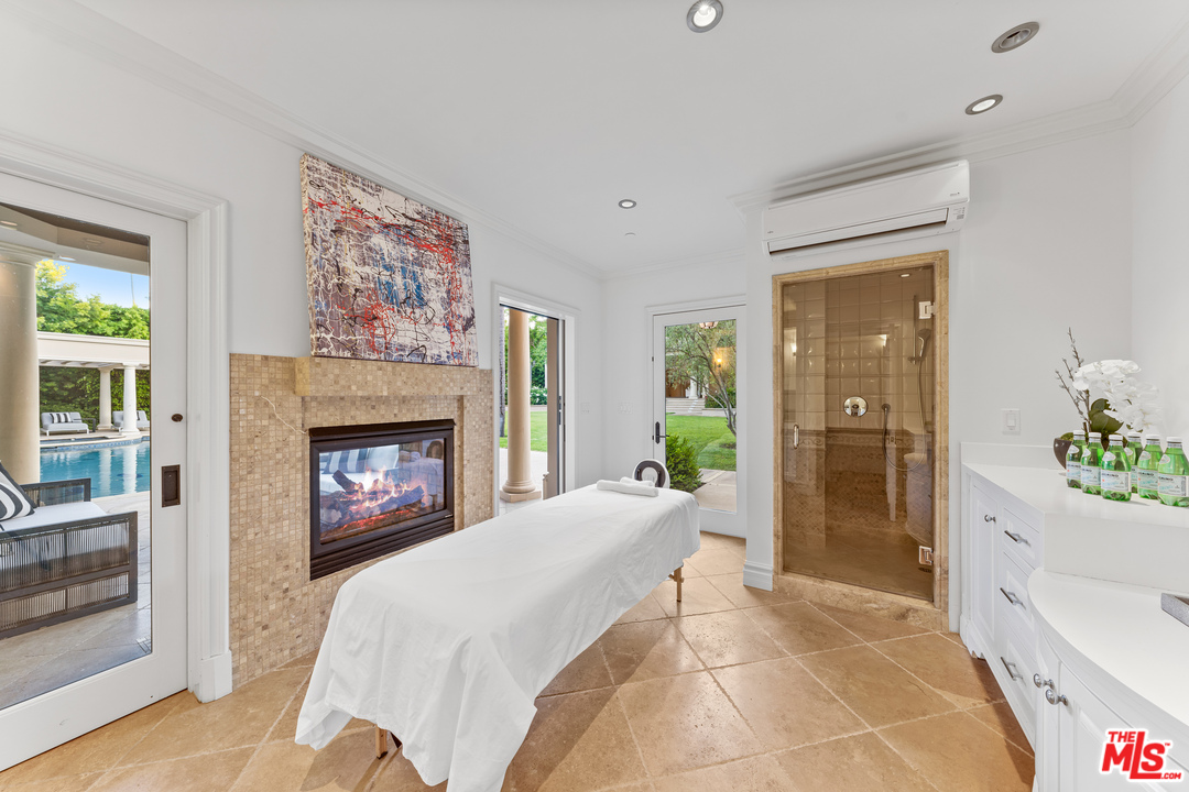 210 North Rockingham Avenue Los Angeles, CA 90049 - Photo 47 of 50 a spacious bedroom with a bed and a fireplace