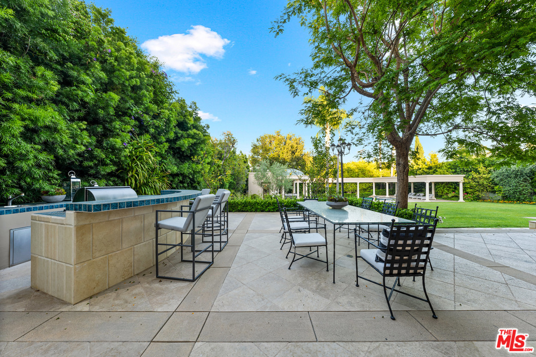 210 North Rockingham Avenue Los Angeles, CA 90049 - Photo 48 of 50 a view of a patio with table and chairs potted plants and large tree