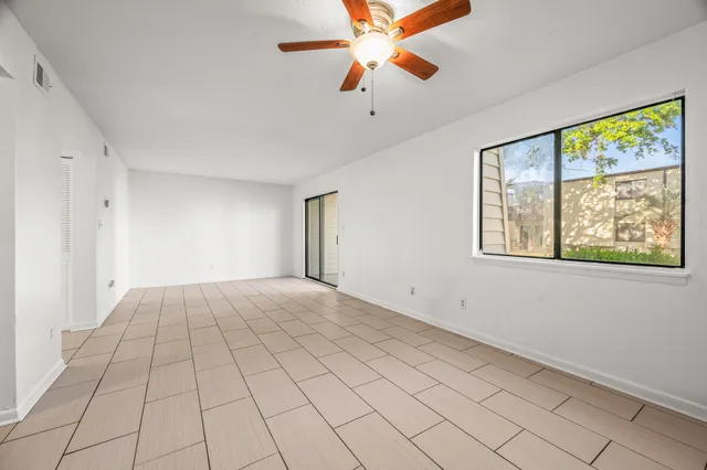 a view of an empty room with window and chandelier fan