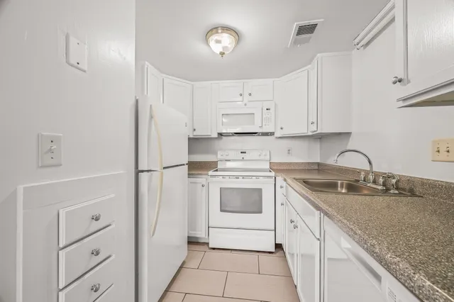 a kitchen with granite countertop a sink stove and refrigerator