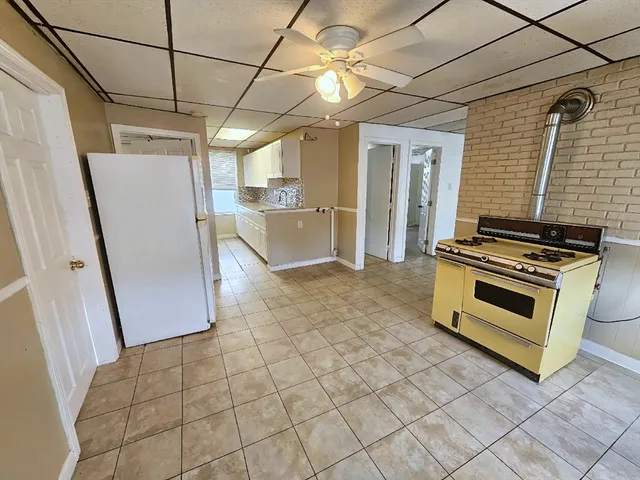 a view of kitchen with refrigerator and white cabinets